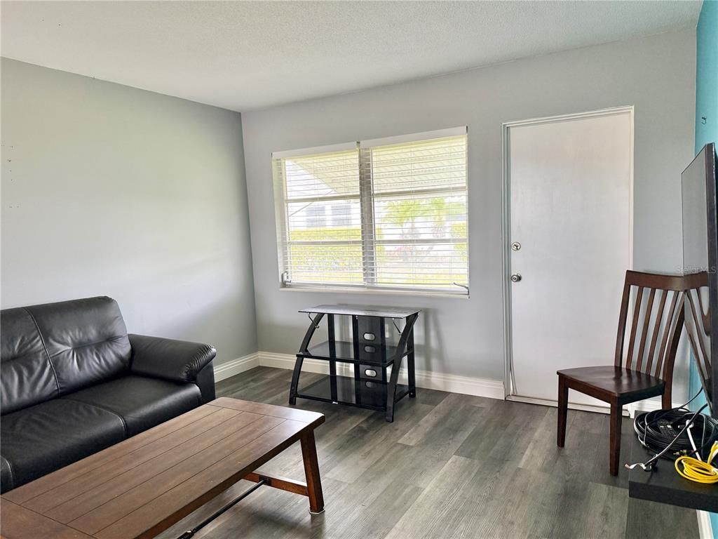 A bedroom features gray walls, wood-look flooring, a wooden dresser with a mirror, and a window — 2217 HOPKINS DRIVE W UNIT 2217, BRADENTON, FL