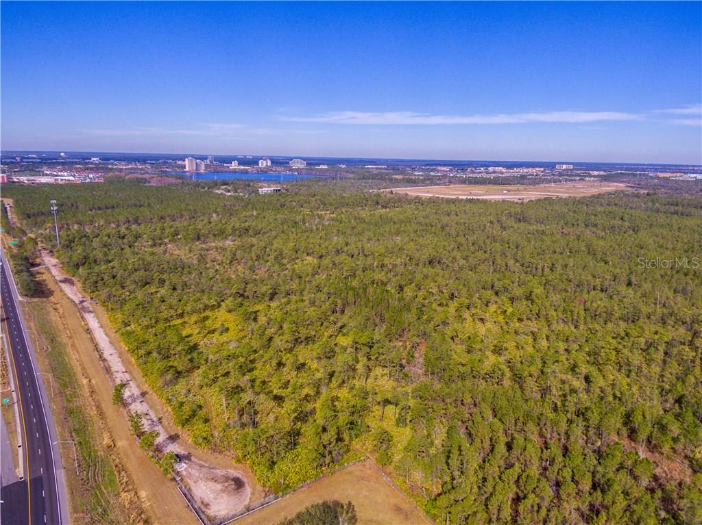 An aerial view shows a large, wooded vacant lot adjacent to a paved road — INTERNATIONAL DRIVE, ORLANDO, FL