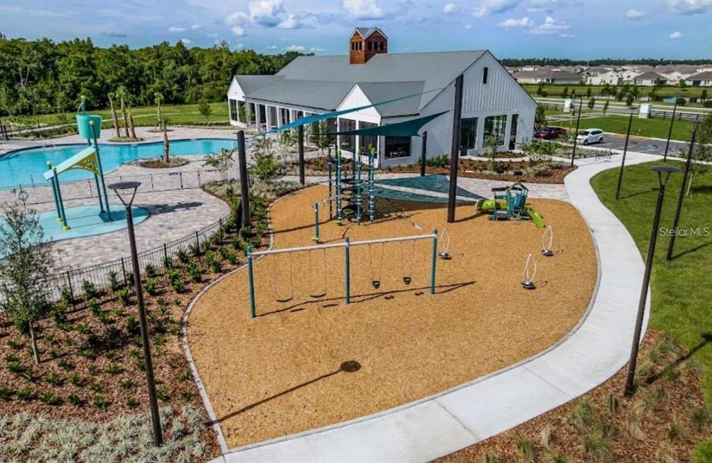 An aerial view shows a playground with swings and a swimming pool beside a building — 6877 BOTANIC BLVD BOULEVARD, HARMONY, FL