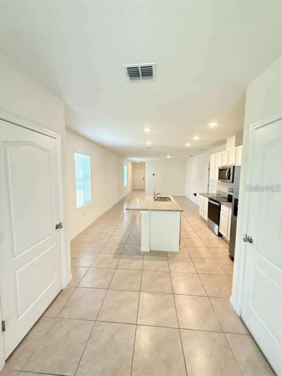 A kitchen with a central island, light-colored cabinets, and tile flooring — 6877 BOTANIC BLVD BOULEVARD, HARMONY, FL