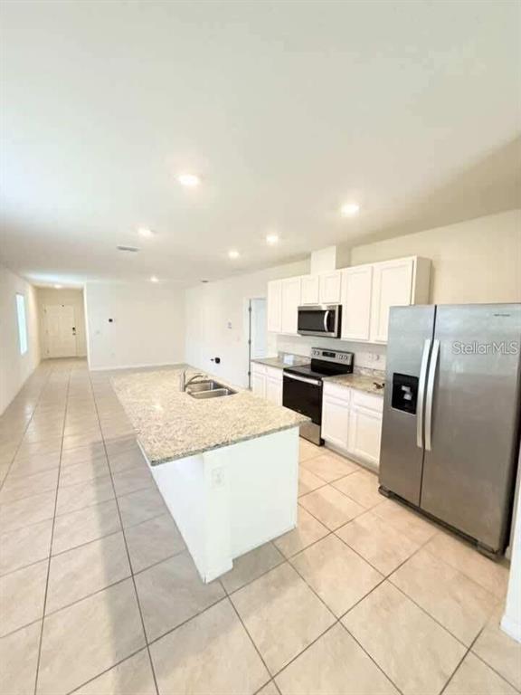 A kitchen with white cabinets, granite countertops, a center island, and stainless steel appliances — 6877 BOTANIC BLVD BOULEVARD, HARMONY, FL