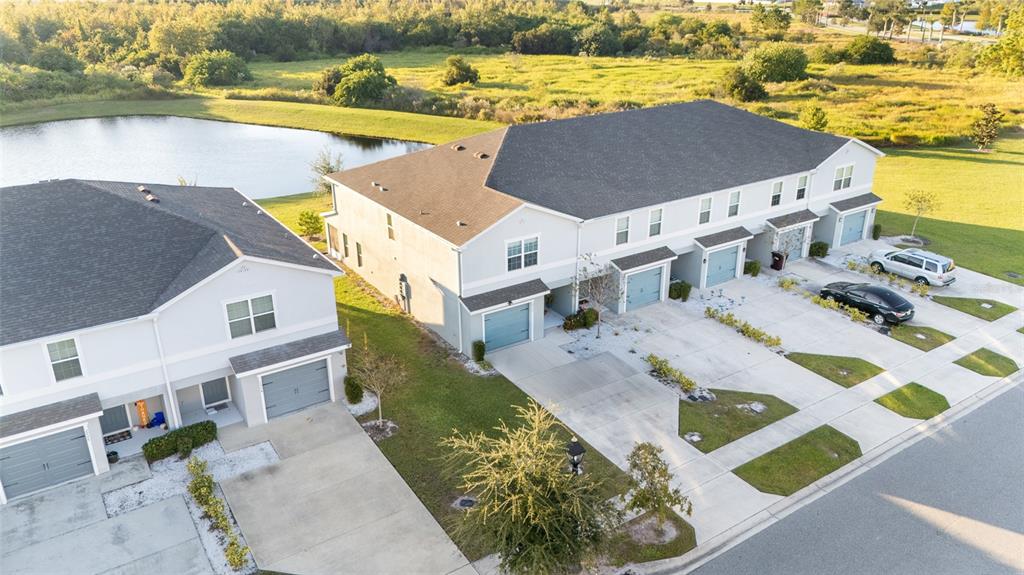 An aerial view shows two multi-unit residential buildings with gray garages and a nearby pond — 2922 FIELDWOOD CIRCLE, ST CLOUD, FL