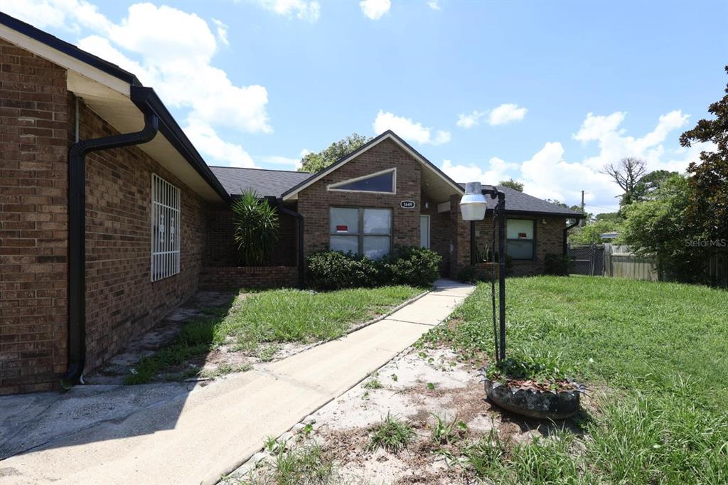 A brick house with a concrete walkway, a front yard, and a decorative tire planter — 1649 PENDLETON STREET, DELTONA, FL