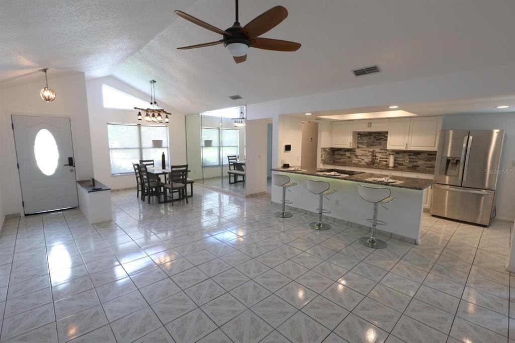 An open-concept kitchen and dining area features white cabinets, tile flooring, and a ceiling fan — 1649 PENDLETON STREET, DELTONA, FL