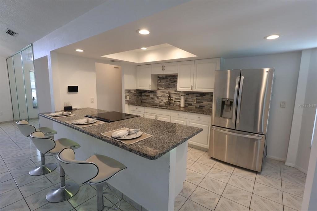 A kitchen features white cabinets, granite countertops, a breakfast bar, and stainless steel appliances — 1649 PENDLETON STREET, DELTONA, FL