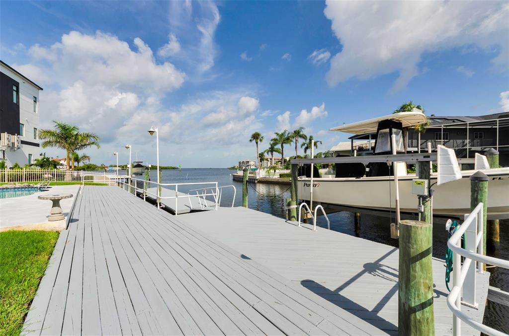 A two-story house with gray siding, a paved driveway, and a covered ground-level parking area — 8001 BRIGHTON DRIVE, PORT RICHEY, FL