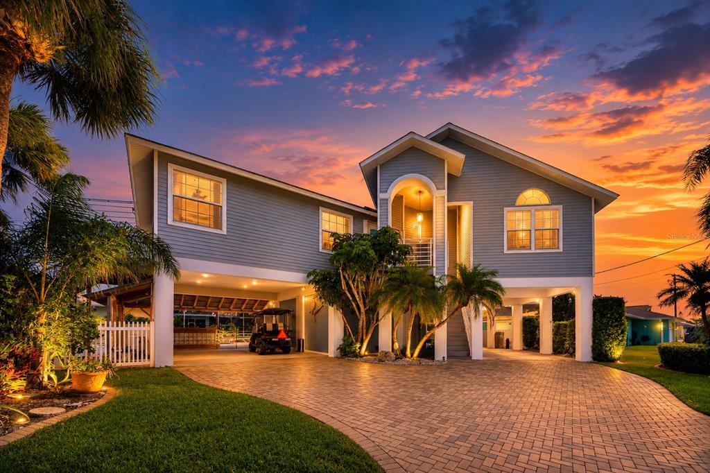A kidney-shaped swimming pool sits on a patio overlooking a canal at sunset — 8001 BRIGHTON DRIVE, PORT RICHEY, FL
