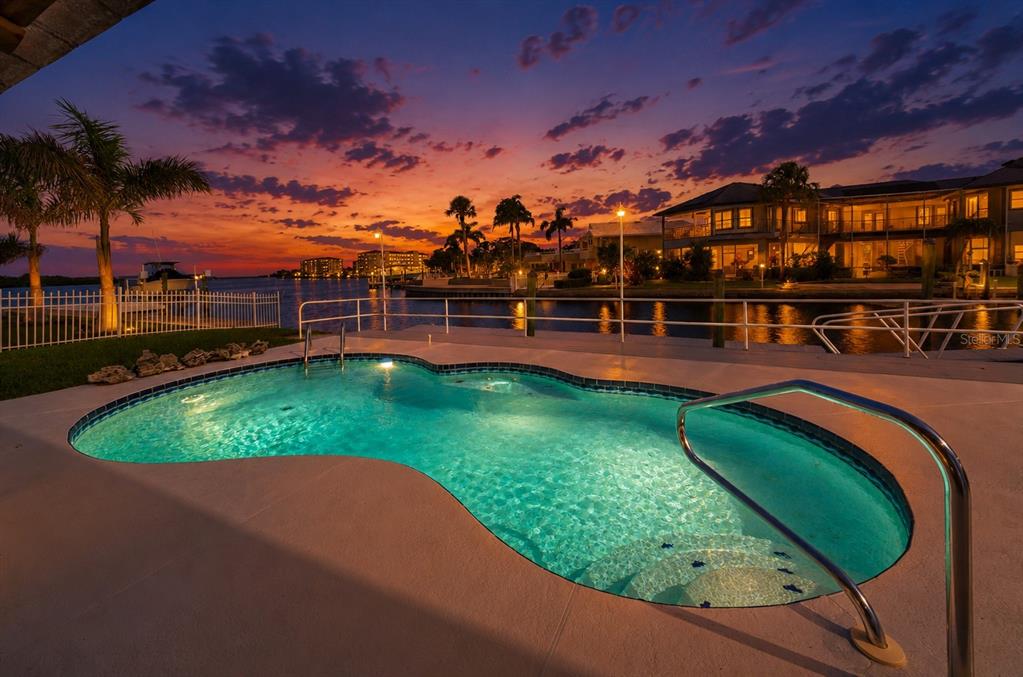 A swimming pool overlooks a canal at sunset with a full moon in the sky — 8001 BRIGHTON DRIVE, PORT RICHEY, FL
