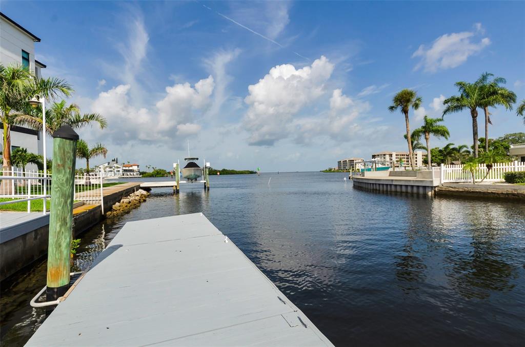 A grassy backyard leads to a concrete dock with patio furniture and a docked boat — 8001 BRIGHTON DRIVE, PORT RICHEY, FL