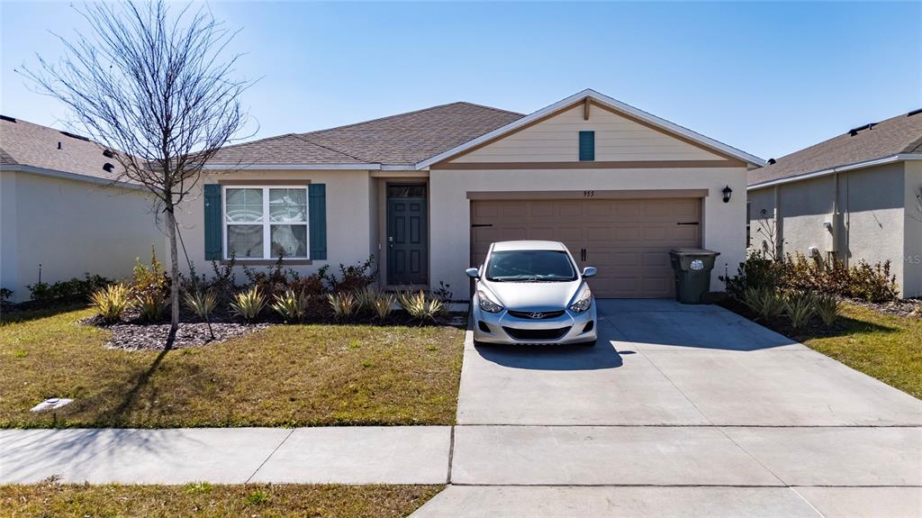 A single-story house with a beige stucco exterior, a two-car garage, and a front driveway — 955 BEAR HAMMOCK DRIVE, UMATILLA, FL