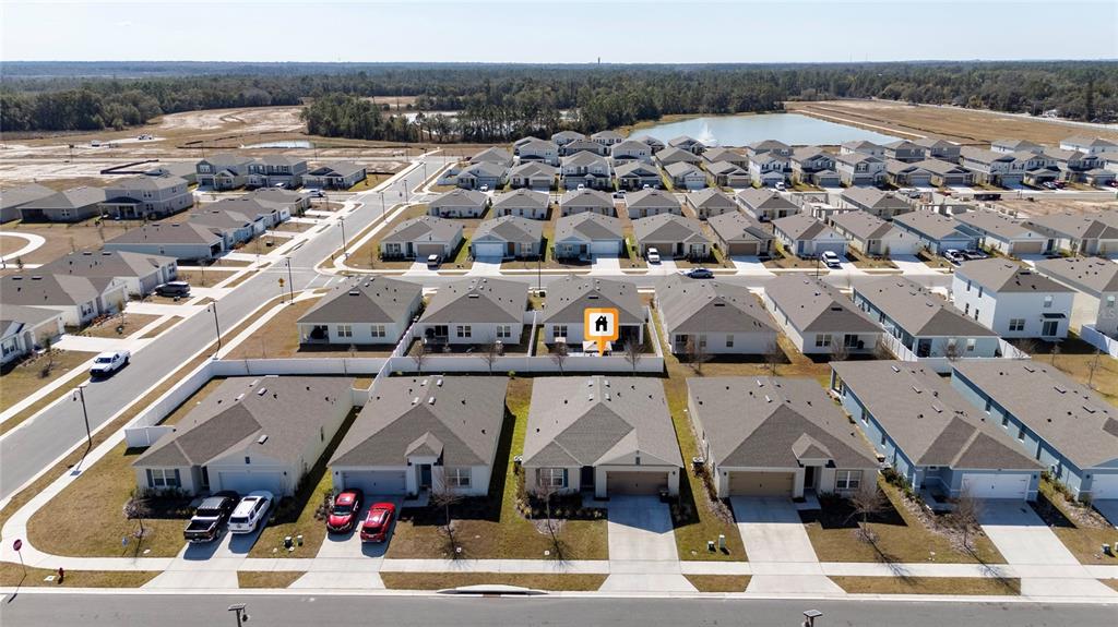 An aerial view shows a suburban neighborhood with many single-family homes and a small pond — 955 BEAR HAMMOCK DRIVE, UMATILLA, FL