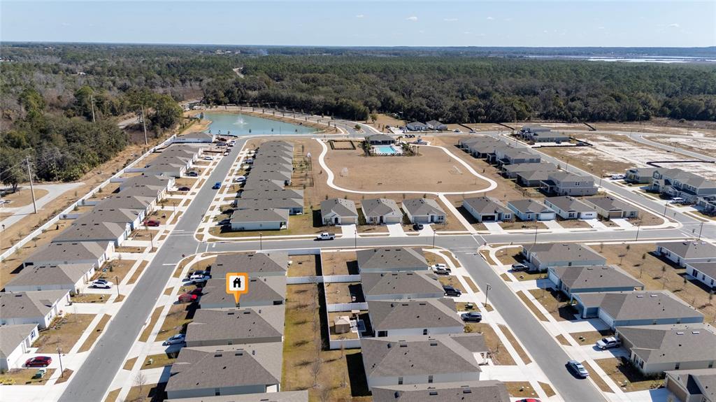 This aerial view shows a suburban neighborhood with houses, a community pool, and a pond — 955 BEAR HAMMOCK DRIVE, UMATILLA, FL