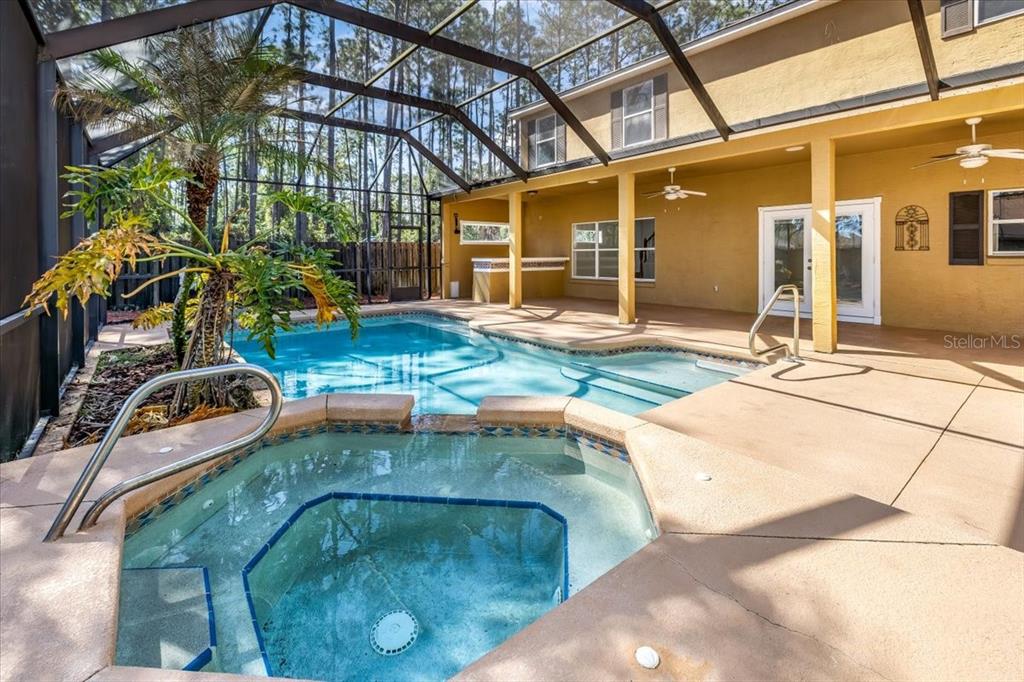 A screened-in patio features a swimming pool, a raised hot tub, and a covered porch — 4 LAKE CHARLES PLACE, PALM COAST, FL