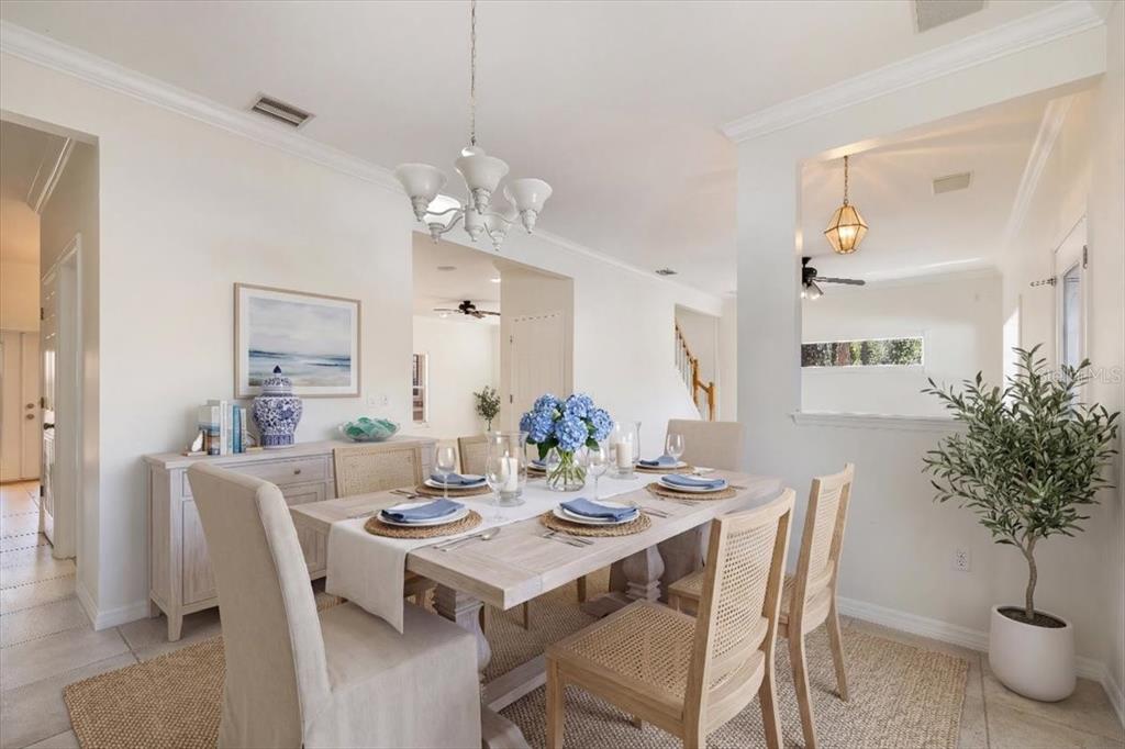 A dining room features a light wood table, upholstered and cane chairs, and a chandelier — 4 LAKE CHARLES PLACE, PALM COAST, FL