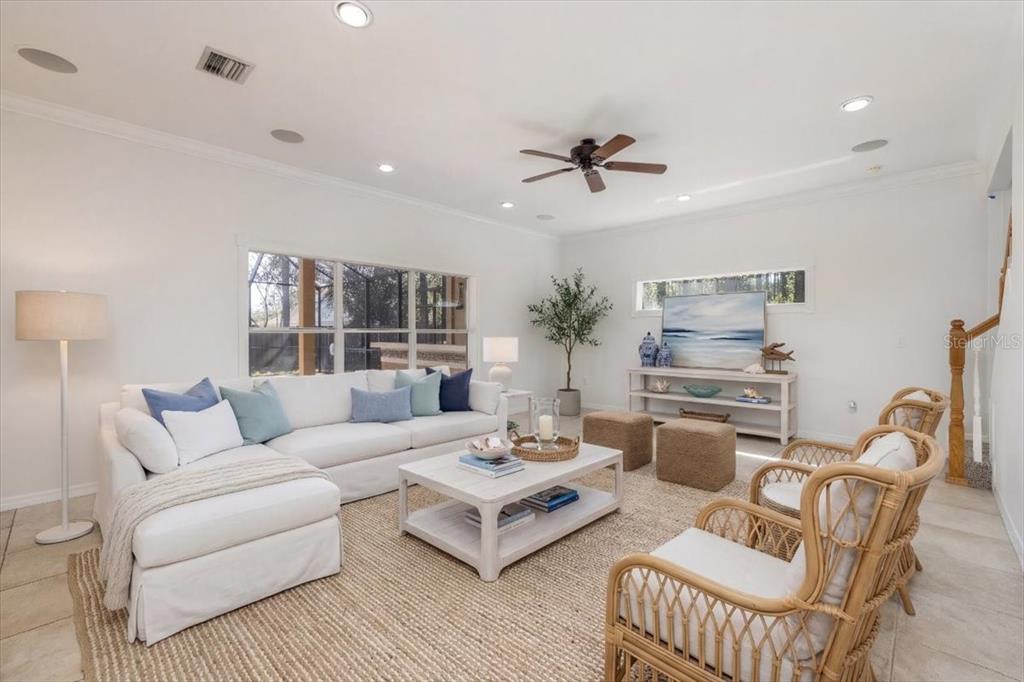 A bright living room features a white sectional sofa, rattan chairs, and a coffee table — 4 LAKE CHARLES PLACE, PALM COAST, FL
