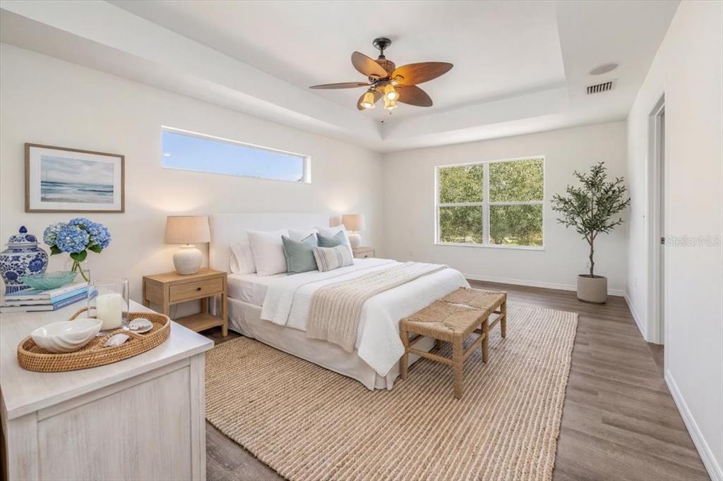 A bright bedroom features a tray ceiling, a ceiling fan, and a neutral color palette — 4 LAKE CHARLES PLACE, PALM COAST, FL