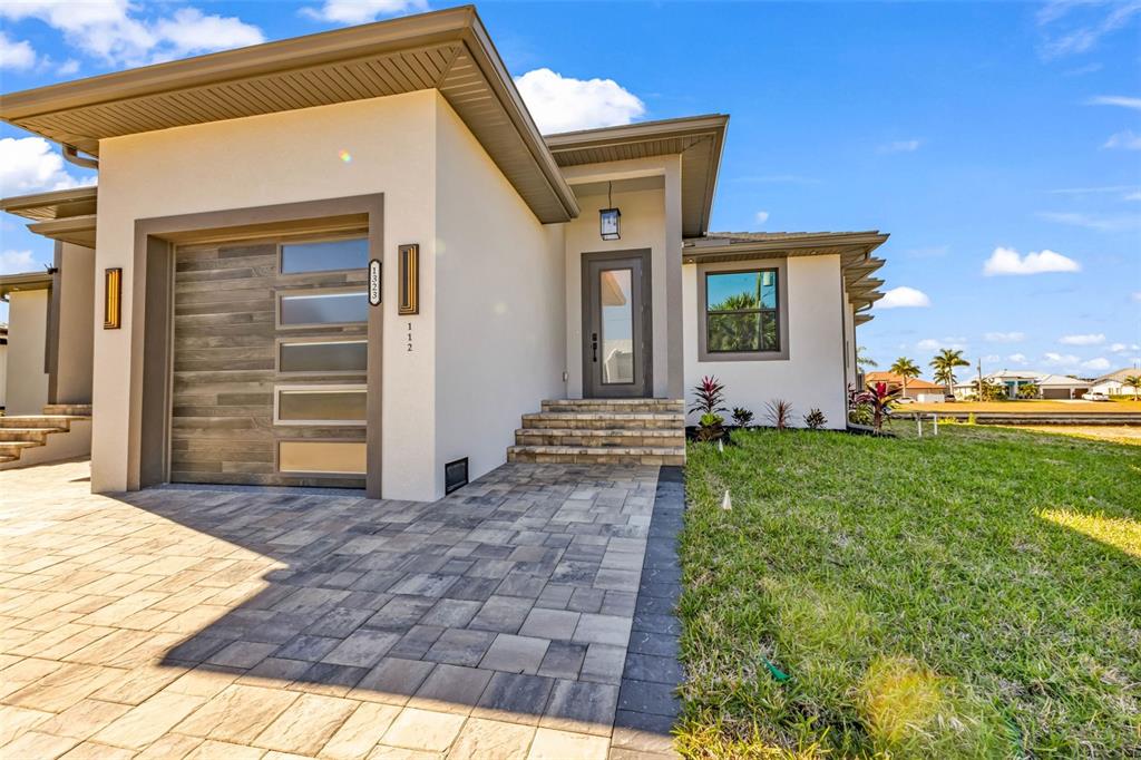 A modern one-story house exterior features a garage, stone steps, and a paved walkway — 1323 WESLEY DRIVE UNIT 112, PUNTA GORDA, FL