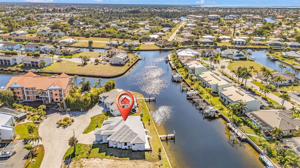 An aerial view shows a waterfront house with a red pin marker on a canal — 1323 WESLEY DRIVE UNIT 112, PUNTA GORDA, FL
