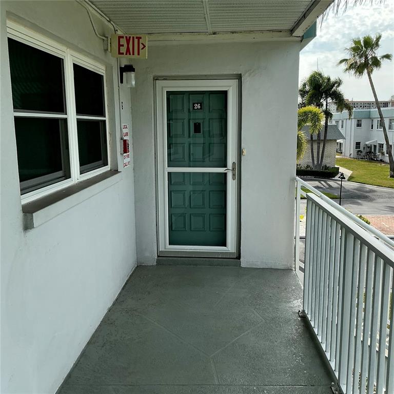 A two-story apartment building features a white exterior, a metal staircase, and a palm tree — 5267 81ST ST N UNIT 26, ST PETERSBURG, FL