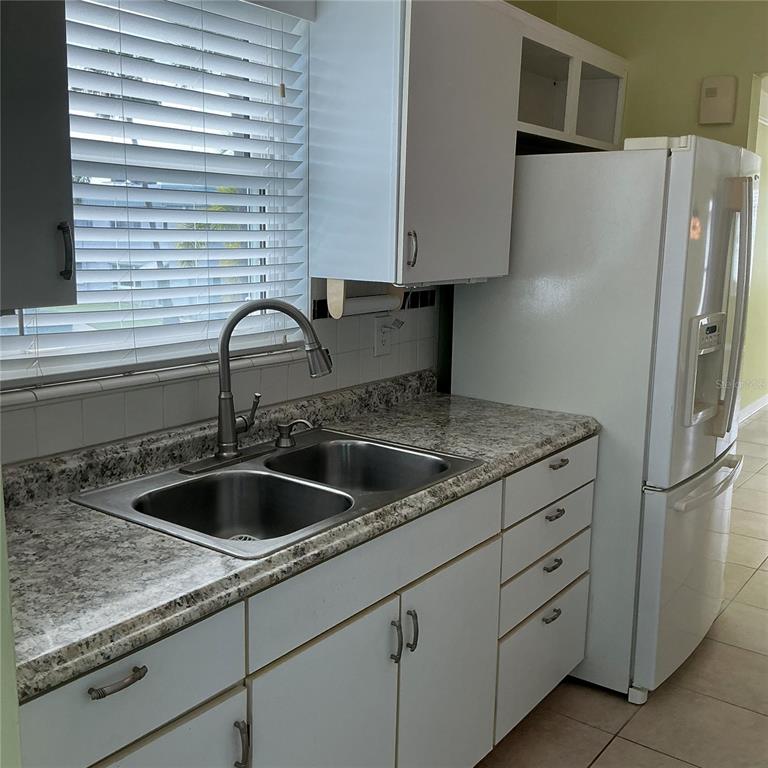 An empty room with light green walls, tiled flooring, a ceiling fan, and an entry door — 5267 81ST ST N UNIT 26, ST PETERSBURG, FL