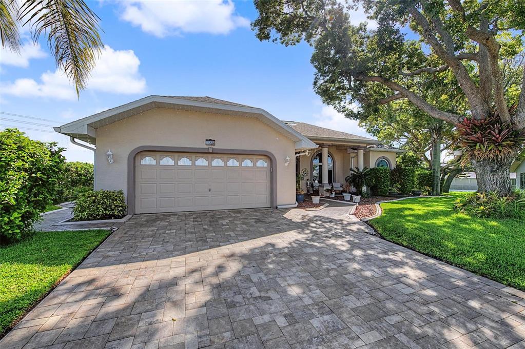 A single-story house with a paved driveway, a two-car garage, and a large tree — 8835 HELMSLY LANE, HUDSON, FL