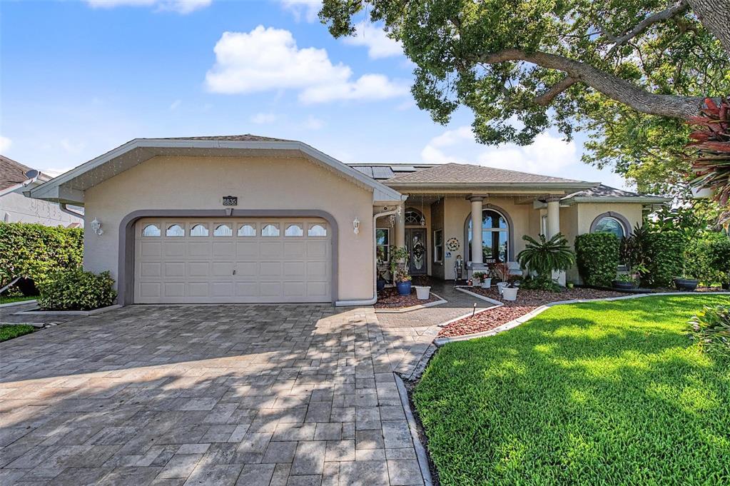 A single-story house with a beige stucco exterior, a paved driveway, and a large tree — 8835 HELMSLY LANE, HUDSON, FL