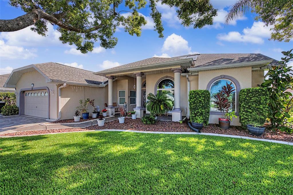 A single-story house with a beige exterior, a two-car garage, and a landscaped front yard — 8835 HELMSLY LANE, HUDSON, FL