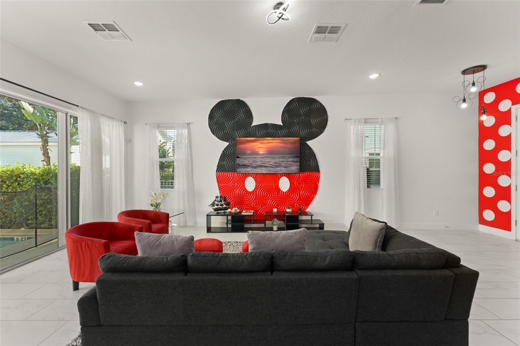 A living room features a large Mickey Mouse-themed wall decoration and a dark sectional sofa — 1531 FAIRVIEW CIRCLE, REUNION, FL