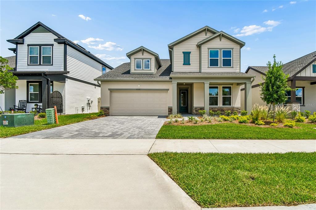 A two-story suburban house with a beige stucco exterior, a two-car garage, and a lawn — 5735 LEAFLET TRAIL, MOUNT DORA, FL