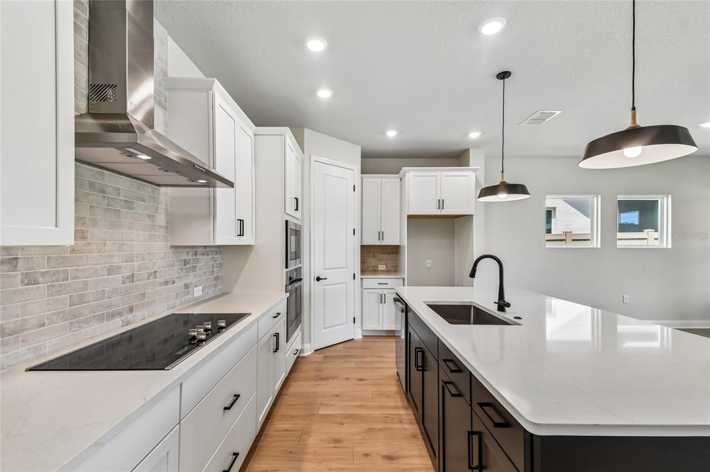 A modern kitchen features white upper cabinets, a dark island, and stainless steel appliances — 5735 LEAFLET TRAIL, MOUNT DORA, FL