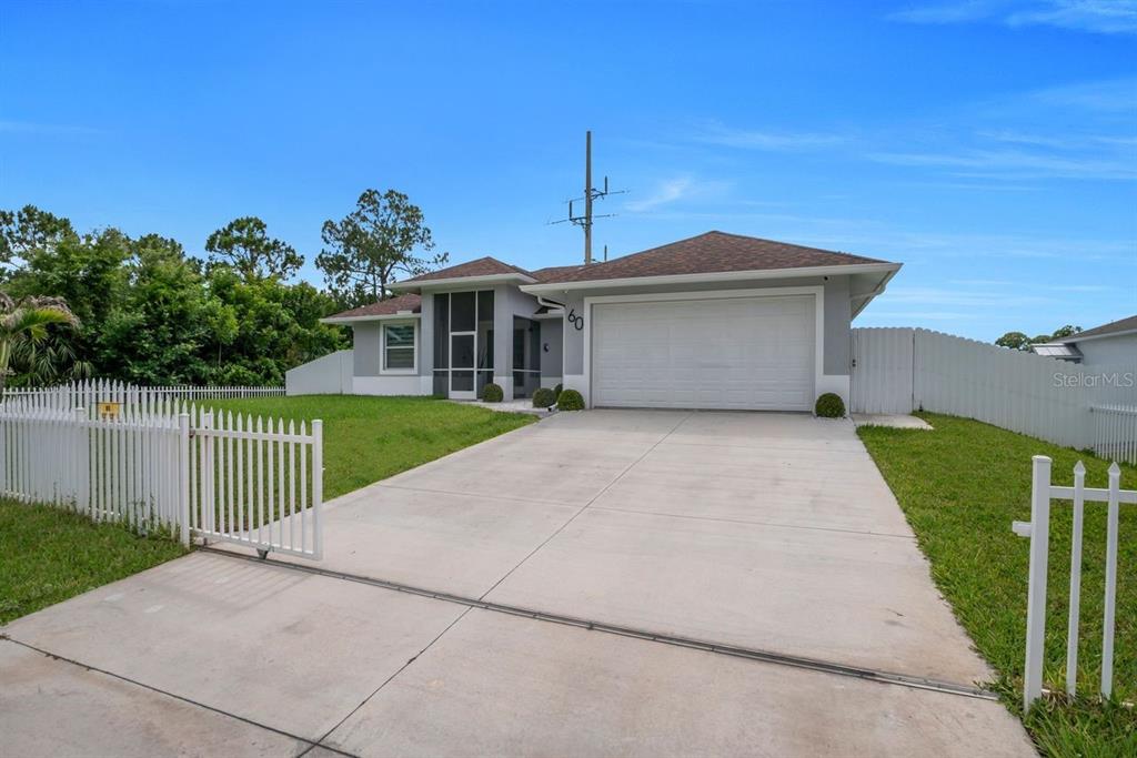 A single-story house with a white garage door and a fenced front yard — 60 FLOYD AVENUE S, LEHIGH ACRES, FL