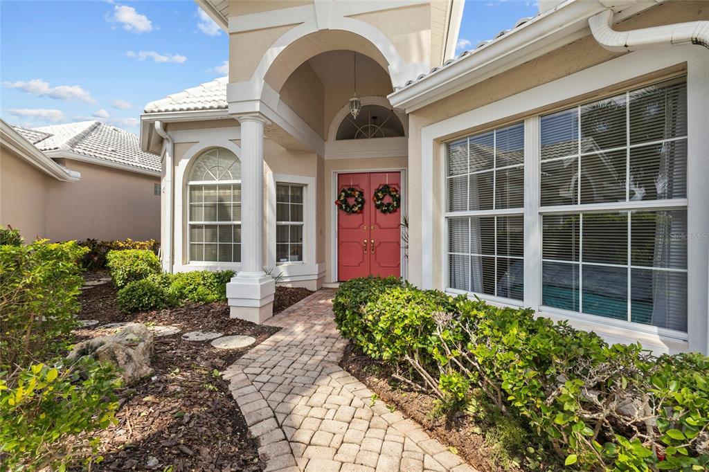 A bright entryway features white double doors, a round floral rug, and a tiered chandelier — 6774 PASEO CASTILLE, SARASOTA, FL