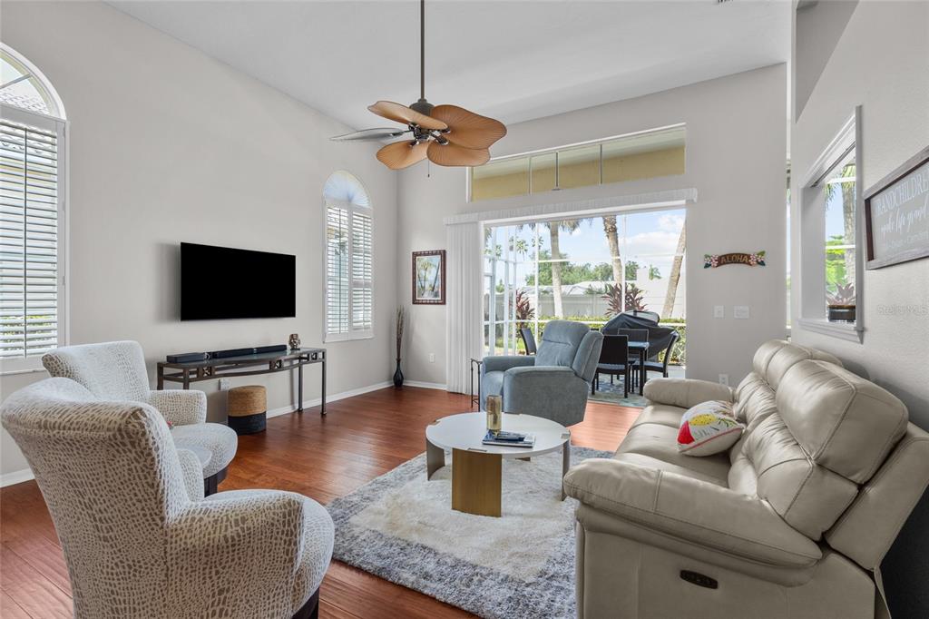 A living room with wood floors, a ceiling fan, and a view of a patio — 6774 PASEO CASTILLE, SARASOTA, FL