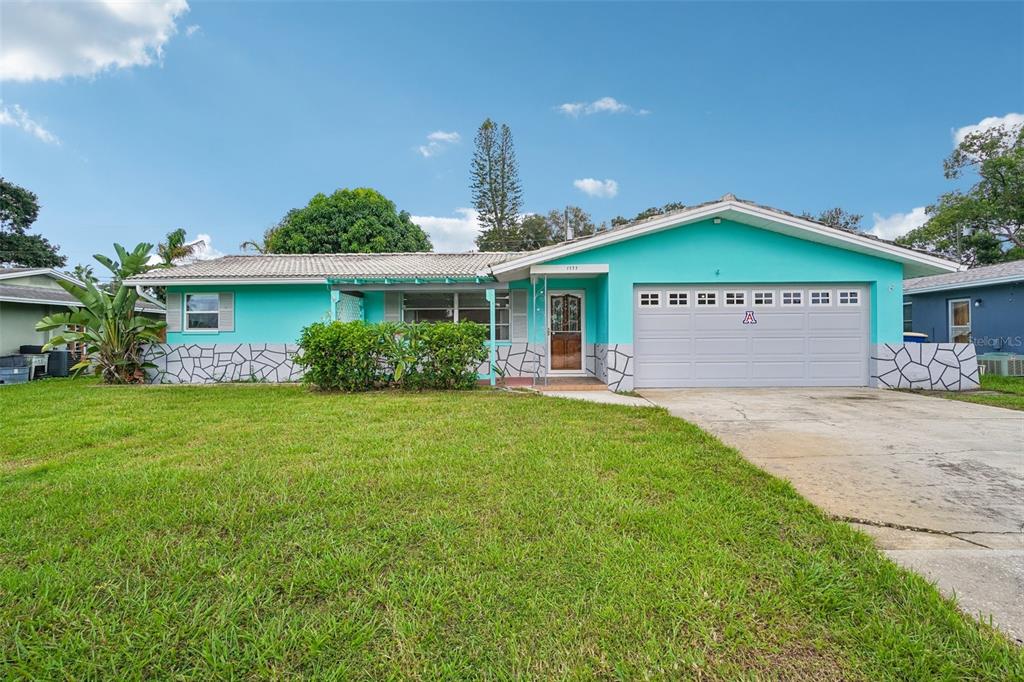 A single-story house with turquoise siding, a stone-patterned base, and an attached two-car garage — 1777 BENTLEY STREET, CLEARWATER, FL