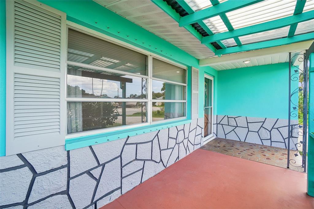 A covered outdoor patio features turquoise walls, a red floor, and decorative stone-patterned siding — 1777 BENTLEY STREET, CLEARWATER, FL