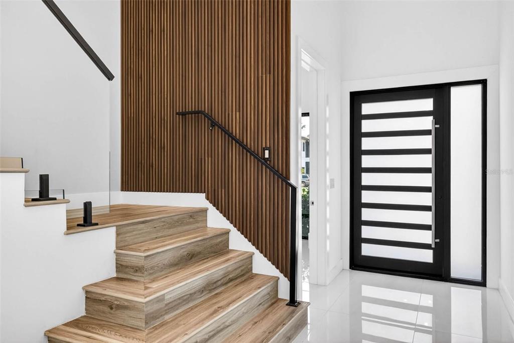 A modern entryway features a wood-slat accent wall, floating staircase, and a black-framed glass door — 4426 W EUCLID AVENUE, TAMPA, FL
