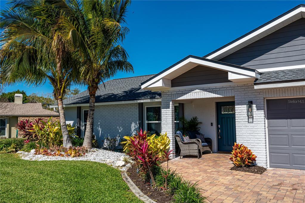 A single-story house with a white brick exterior, a gray garage door, and a palm tree — 7410 2ND AVENUE NW, BRADENTON, FL