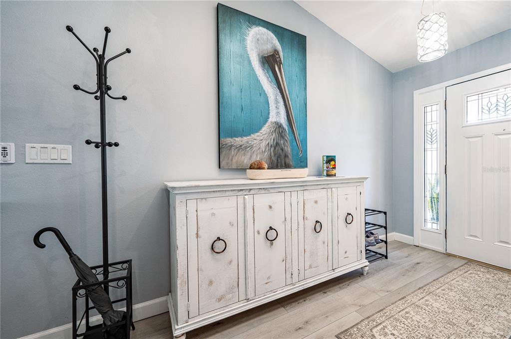 An entryway features a white distressed sideboard, a pelican wall art piece, and a coat rack — 7410 2ND AVENUE NW, BRADENTON, FL