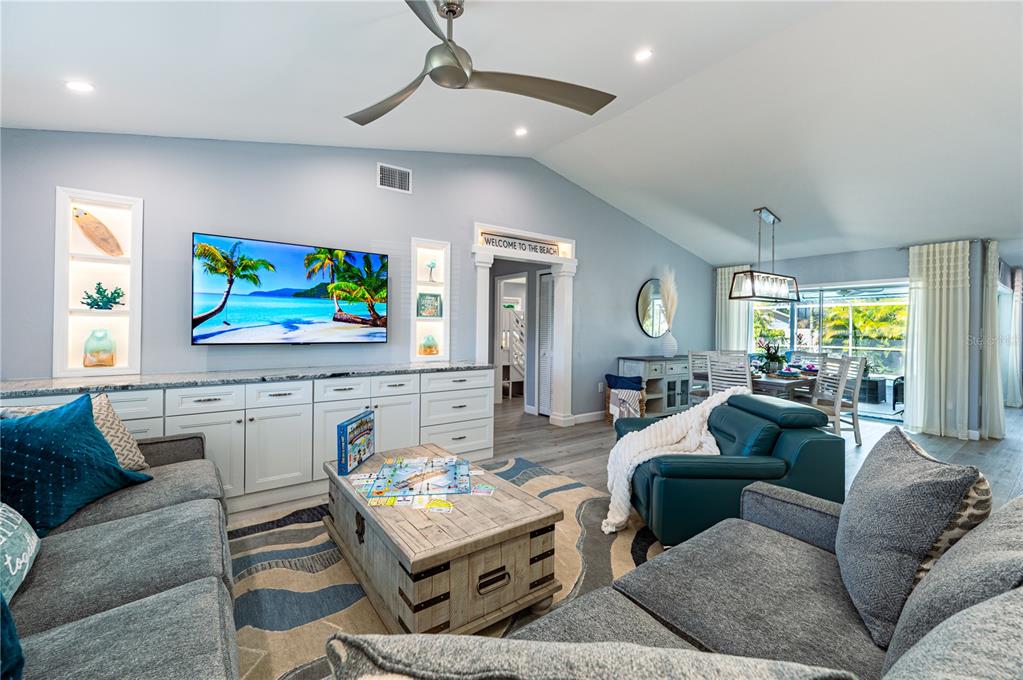 A living room with gray sofas, a wooden coffee table, built-in cabinets, and a television — 7410 2ND AVENUE NW, BRADENTON, FL