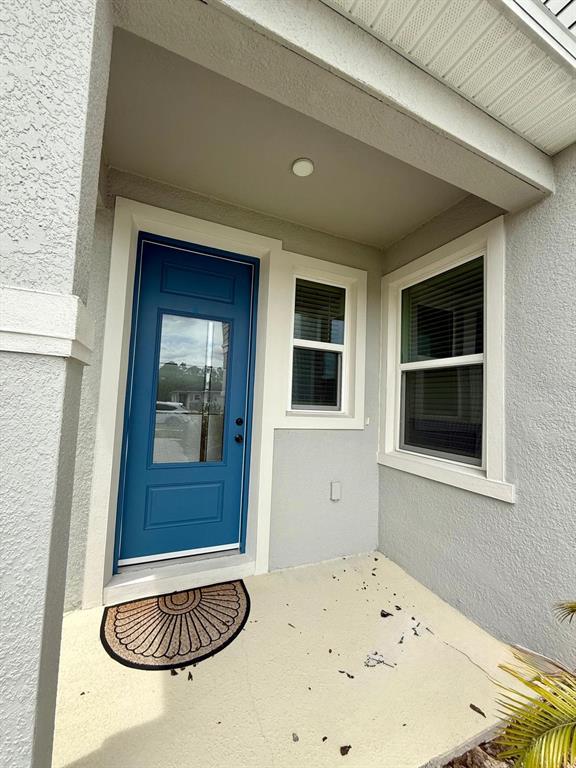 A blue front door with a glass panel sits next to a window on a porch — 16522 BROOK ISLE WAY, CLERMONT, FL
