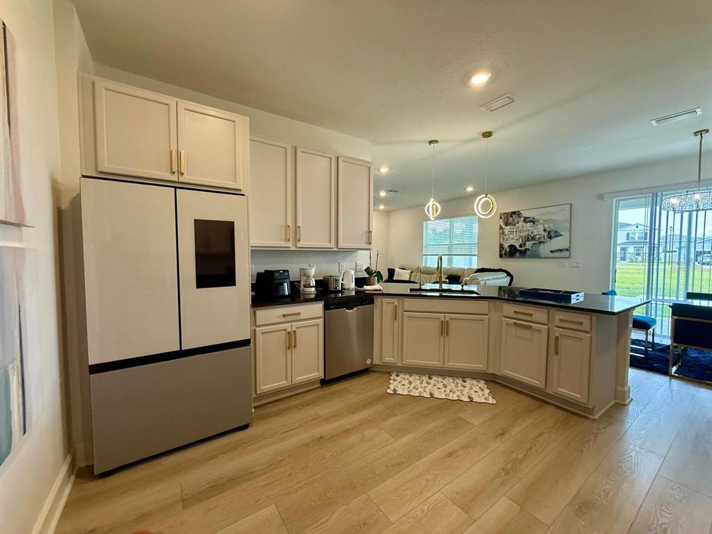 A kitchen with light-colored cabinets, stainless steel appliances, and a dark countertop island — 16522 BROOK ISLE WAY, CLERMONT, FL