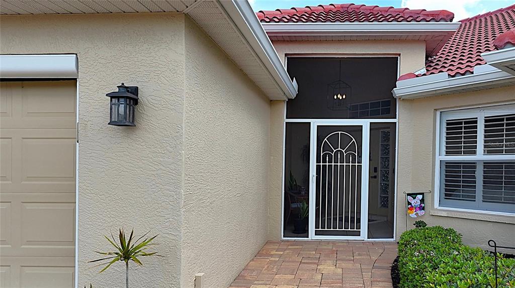 The exterior of a house features a tan stucco wall, a screened entryway, and pavers — 3945 CAPE COLE BOULEVARD, PUNTA GORDA, FL