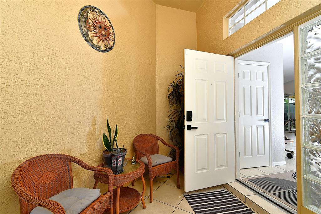 An entryway features a tiled floor, two wicker chairs, a small table, and a white door — 3945 CAPE COLE BOULEVARD, PUNTA GORDA, FL