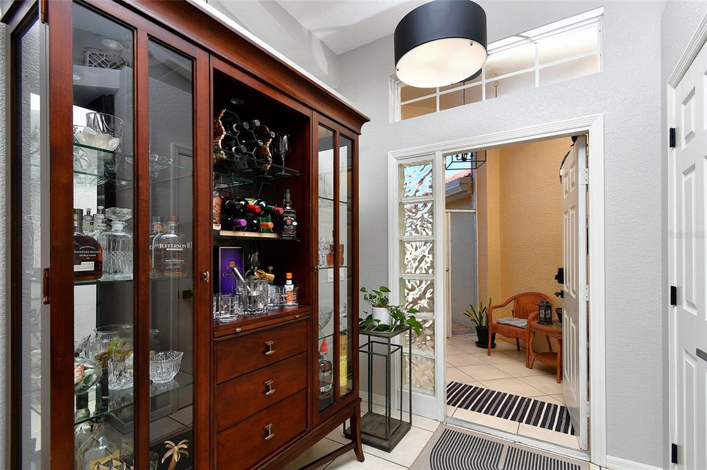 A wooden display cabinet stands in a foyer next to a doorway leading to a patio — 3945 CAPE COLE BOULEVARD, PUNTA GORDA, FL