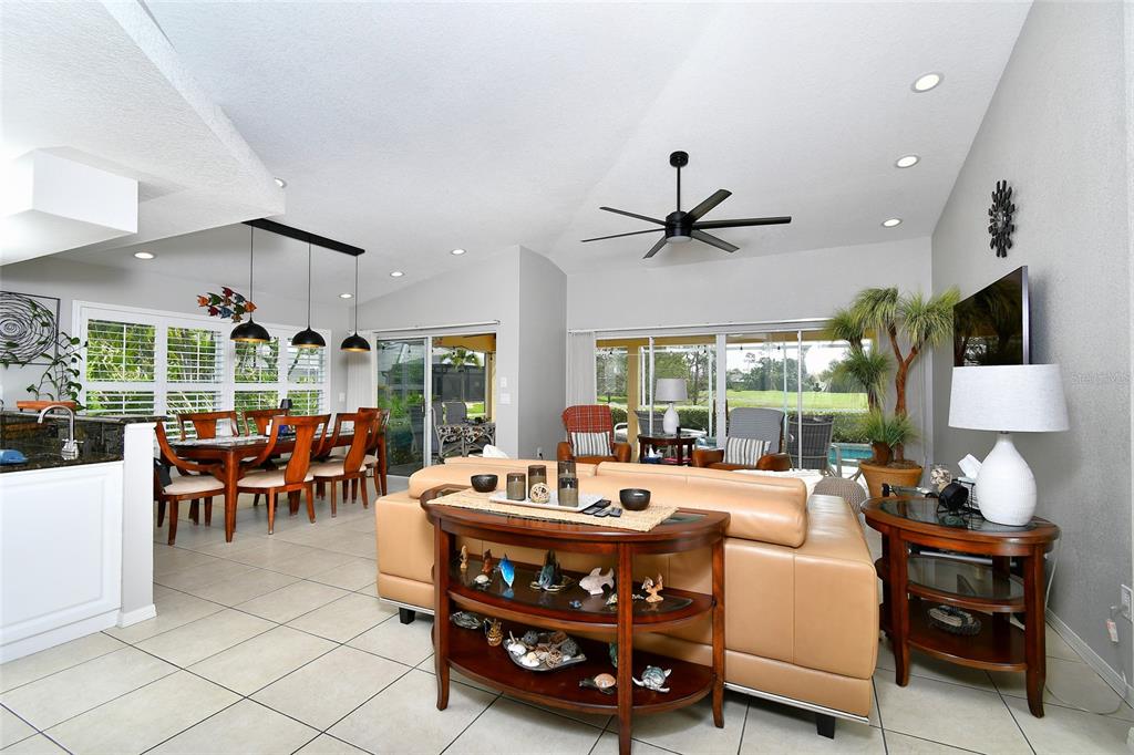 A living and dining area features tile floors, a tan leather sofa, and sliding glass doors — 3945 CAPE COLE BOULEVARD, PUNTA GORDA, FL