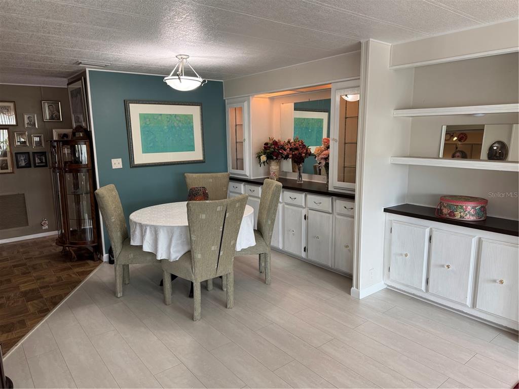 A dining room features a round table, four chairs, built-in cabinetry, and light wood flooring — 6 LAFITTE DRIVE, NOKOMIS, FL