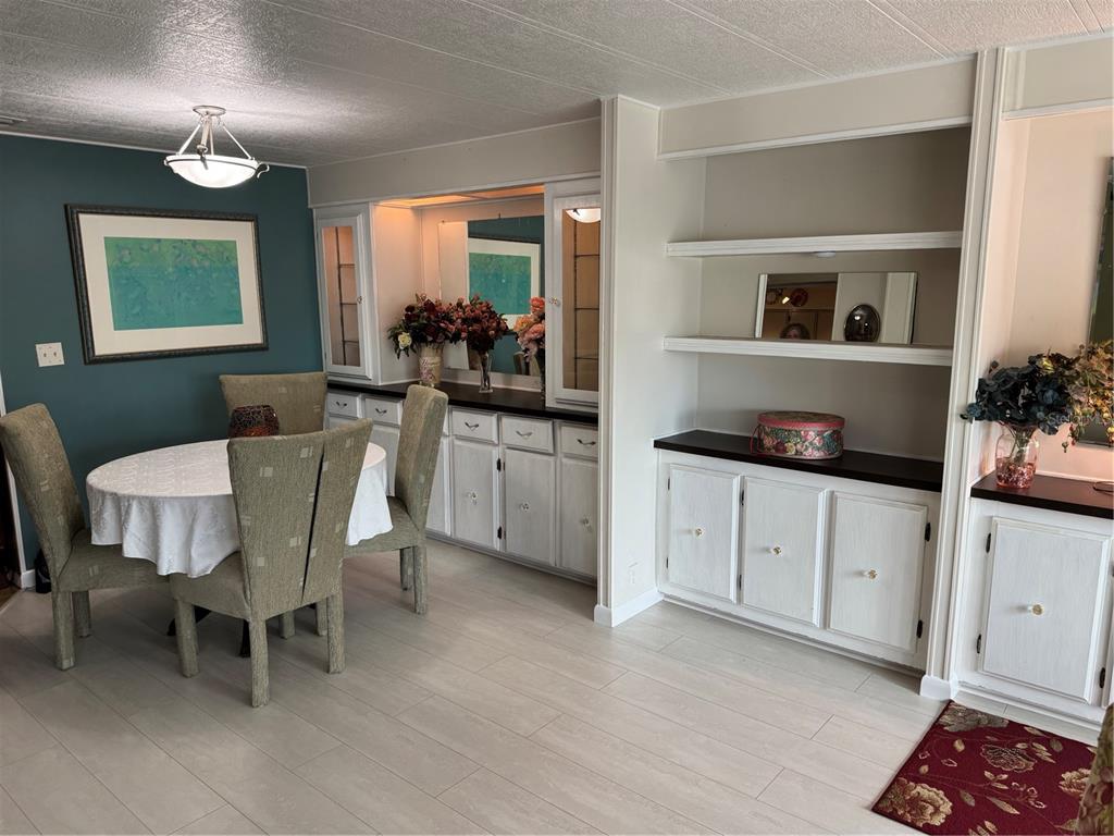 A dining area features a round table, white cabinets, open shelving, and a teal accent wall — 6 LAFITTE DRIVE, NOKOMIS, FL
