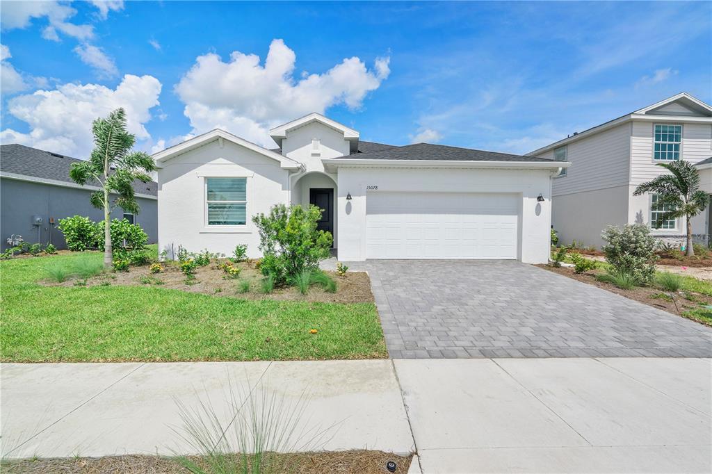 A single-story white house with a paved driveway and a small front yard — 15078 WHITE PEARL ROAD, PUNTA GORDA, FL