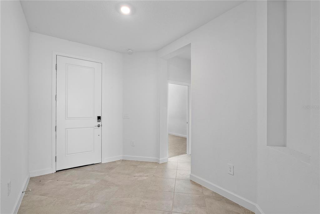 An entryway with white walls, tile flooring, a white door, and a doorway to another room — 15078 WHITE PEARL ROAD, PUNTA GORDA, FL