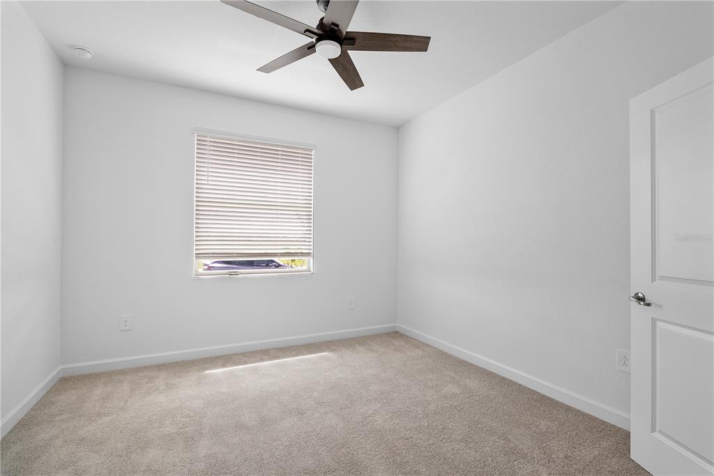 An empty bedroom features white walls, beige carpeting, a ceiling fan, and a single window — 15078 WHITE PEARL ROAD, PUNTA GORDA, FL